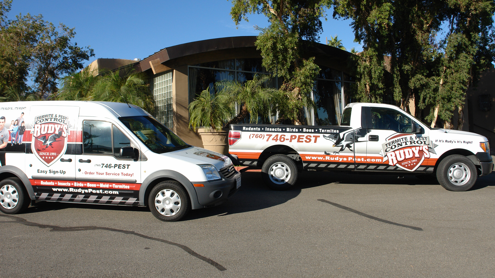 Two Rudy's Pest Control vehicles parked in front of a home